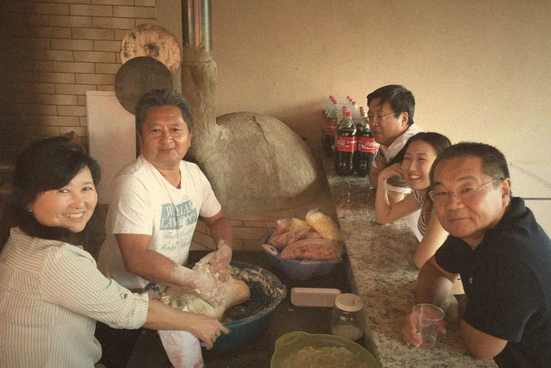 Meu pai preparando a massa em família, no forno a lenha